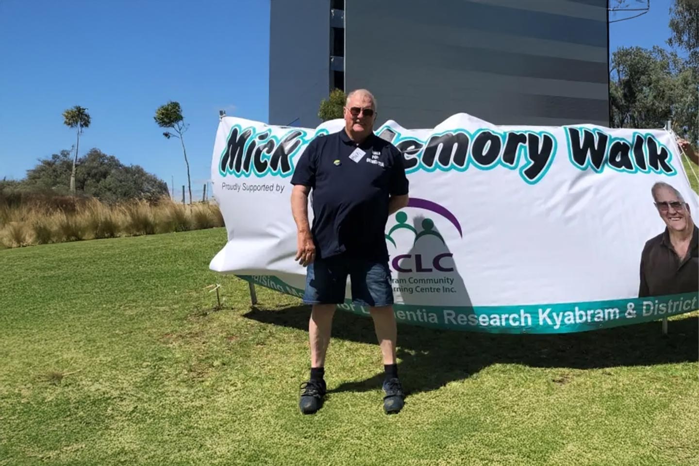 Photo of a man in shorts standing in front of a banner