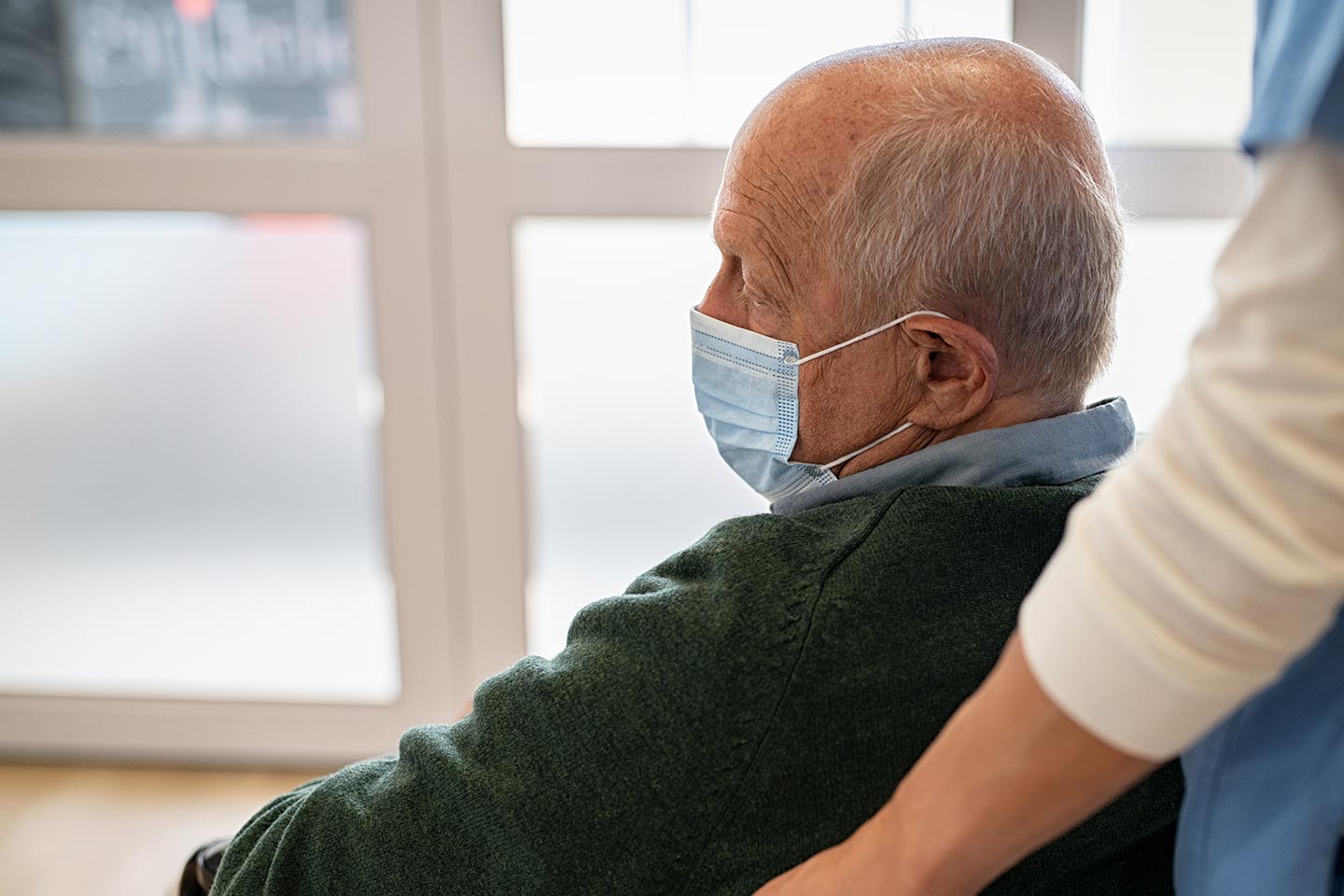 Photo of a man in a green jumper and blue surgical mask