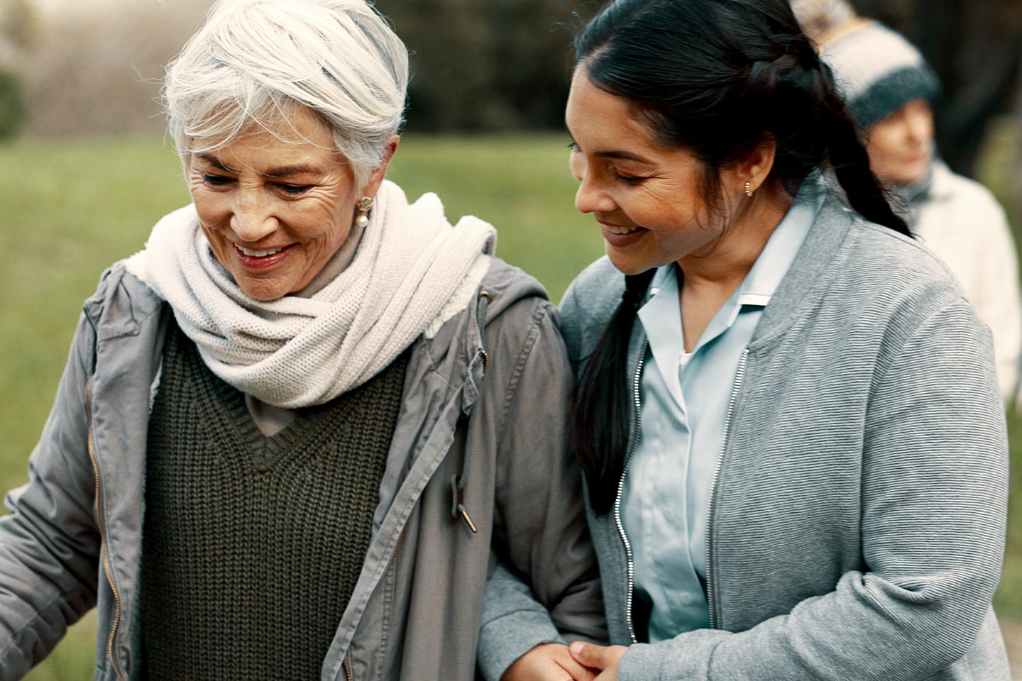 Photo of two women walking arm in arm outdoors