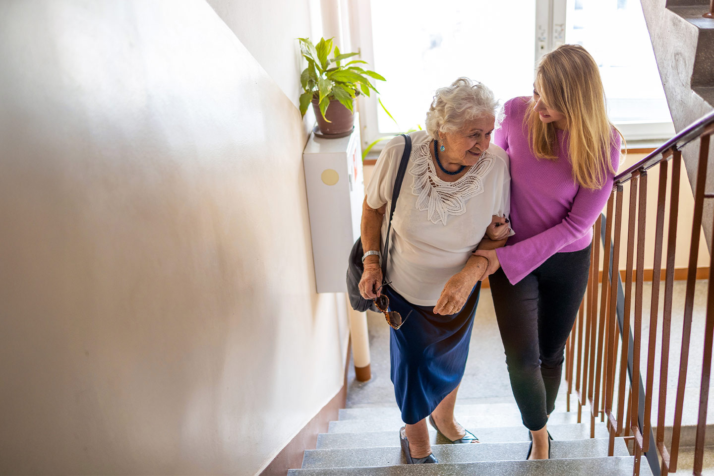 Photo of a woman helping another woman to climb stairs