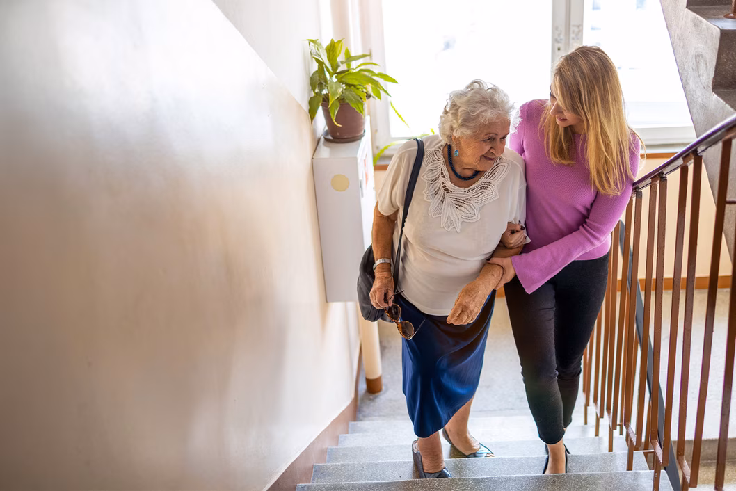 Photo of a woman helping another woman to climb stairs