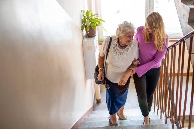 Photo of a woman helping another woman to climb stairs
