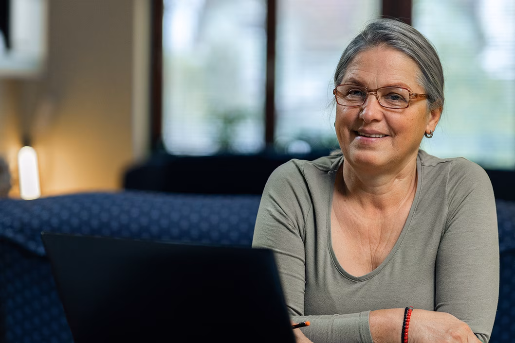 Photo of a woman in a sage green top sitting on a blue couch