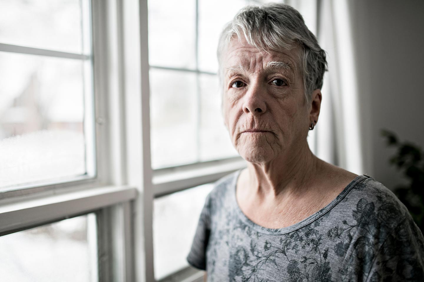 Photo of woman in a grey T shirt standing by a window