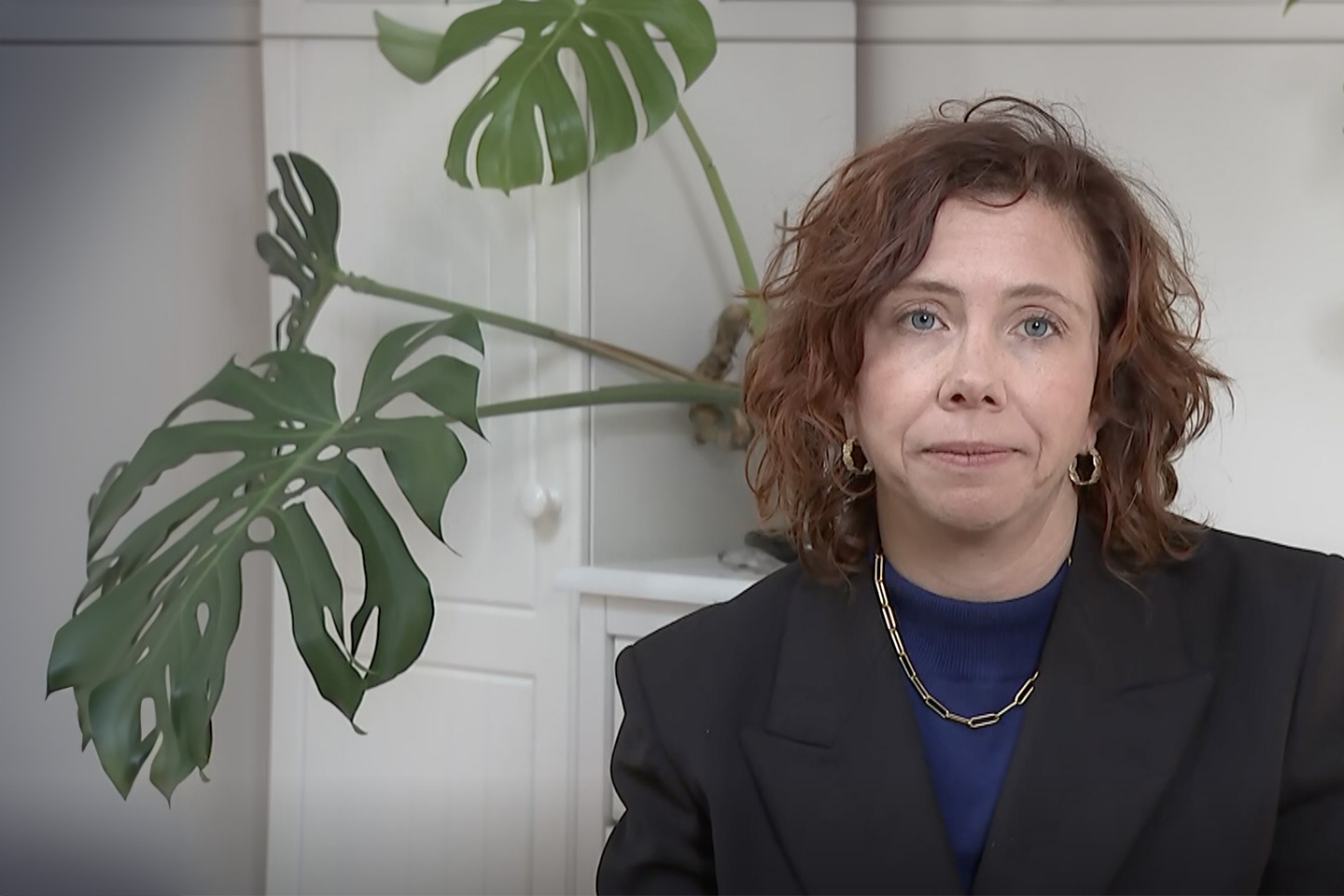 Photo of woman sitting in front of an indoor plant