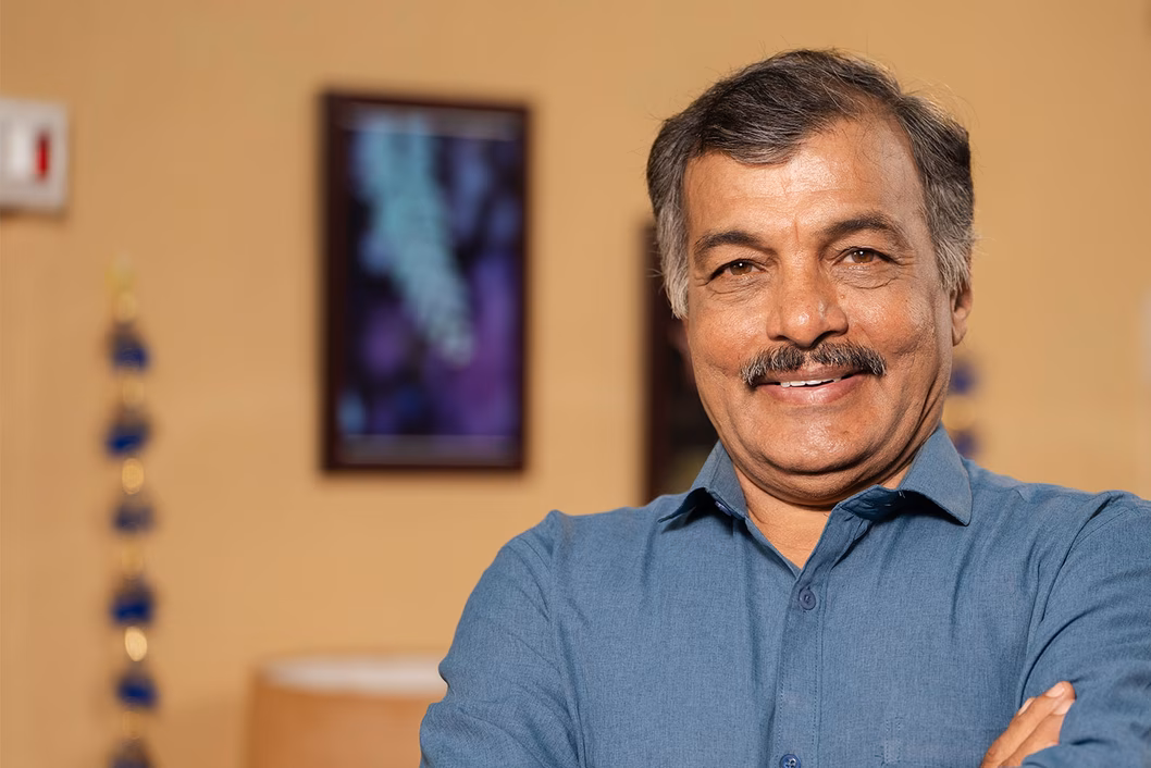 Photo of a smiling man in a blue grey shirt