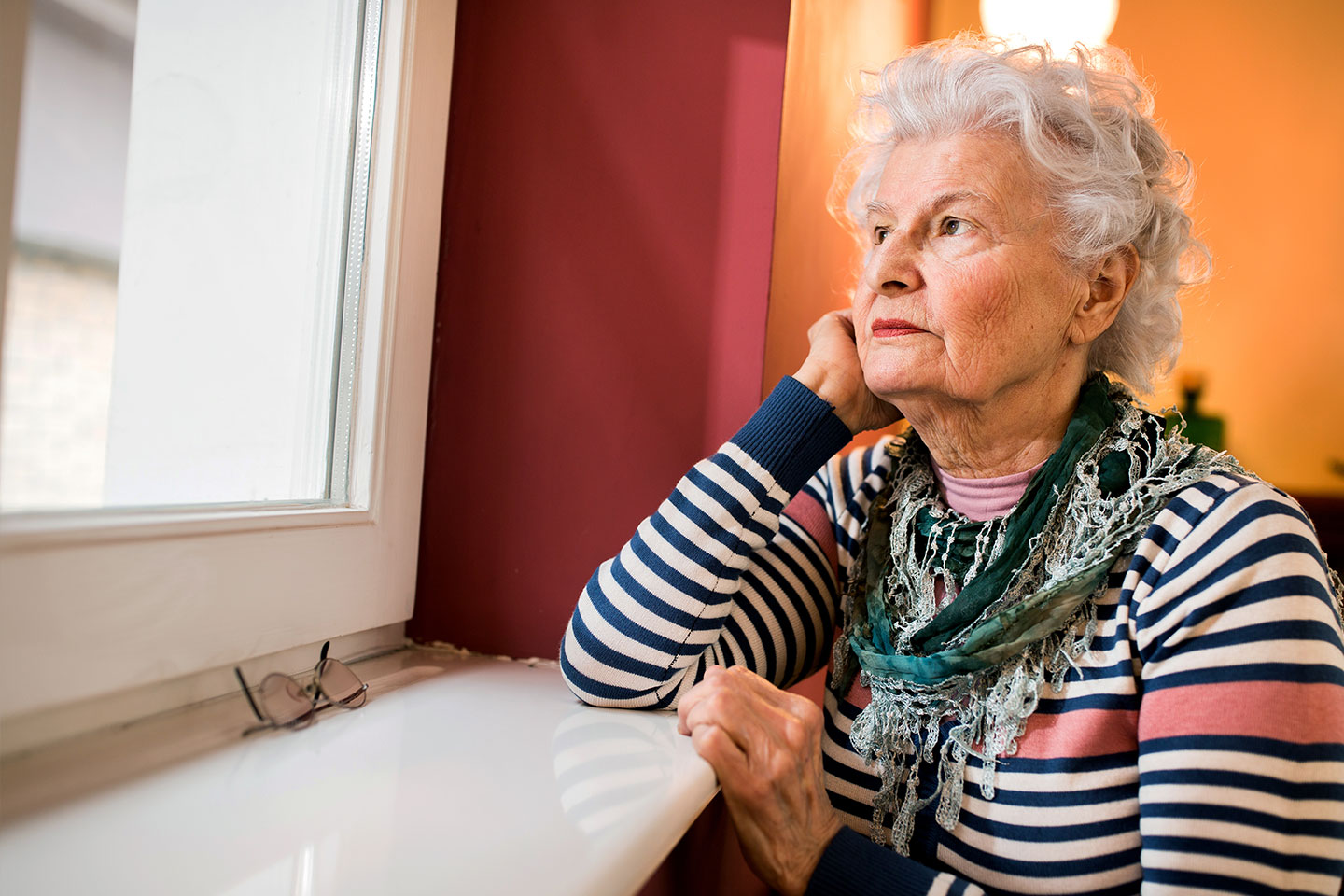 Photo of a woman with a striped top staring out a window