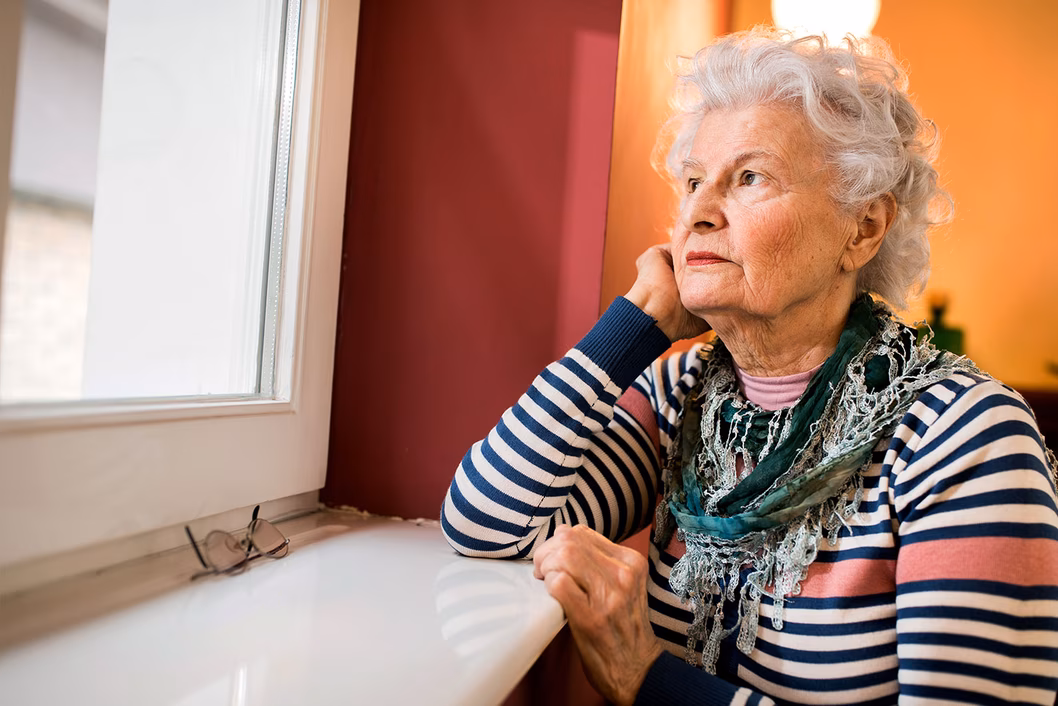 Photo of a woman with a striped top staring out a window