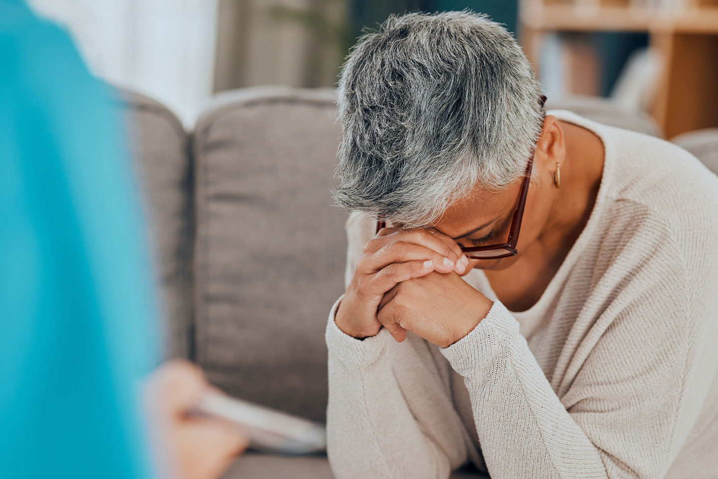 Photo of a woman resting her forehead on her clasped hands