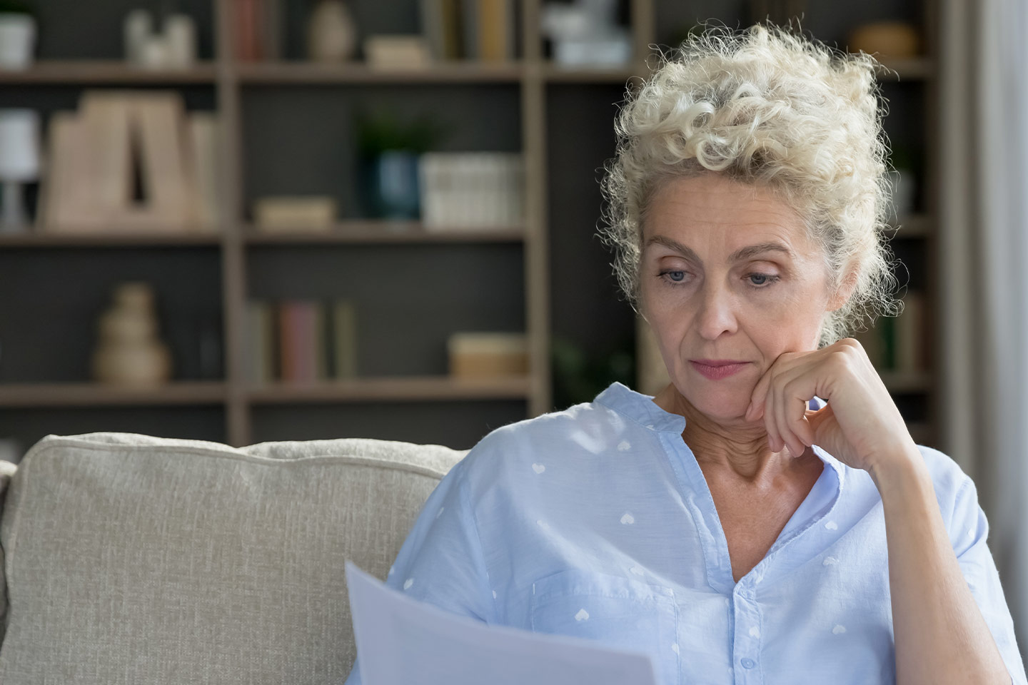 Photo of a woman wearing a blue blouse reading a letter