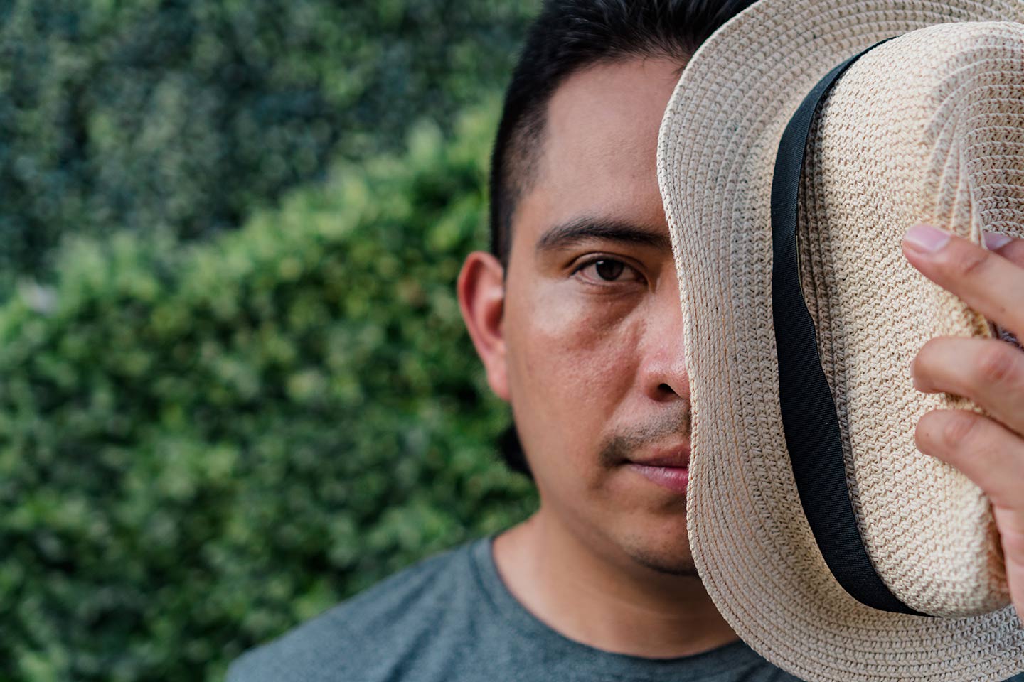 Photo of man holding a hat in front of half his face