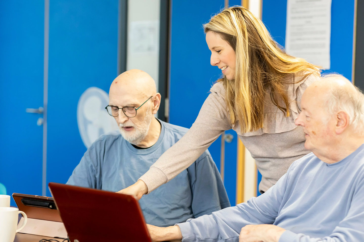 Photo of a woman helping two men with laptops