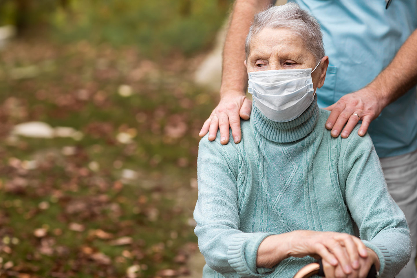 Photo of a woman in a pale green jumper wearing a mask