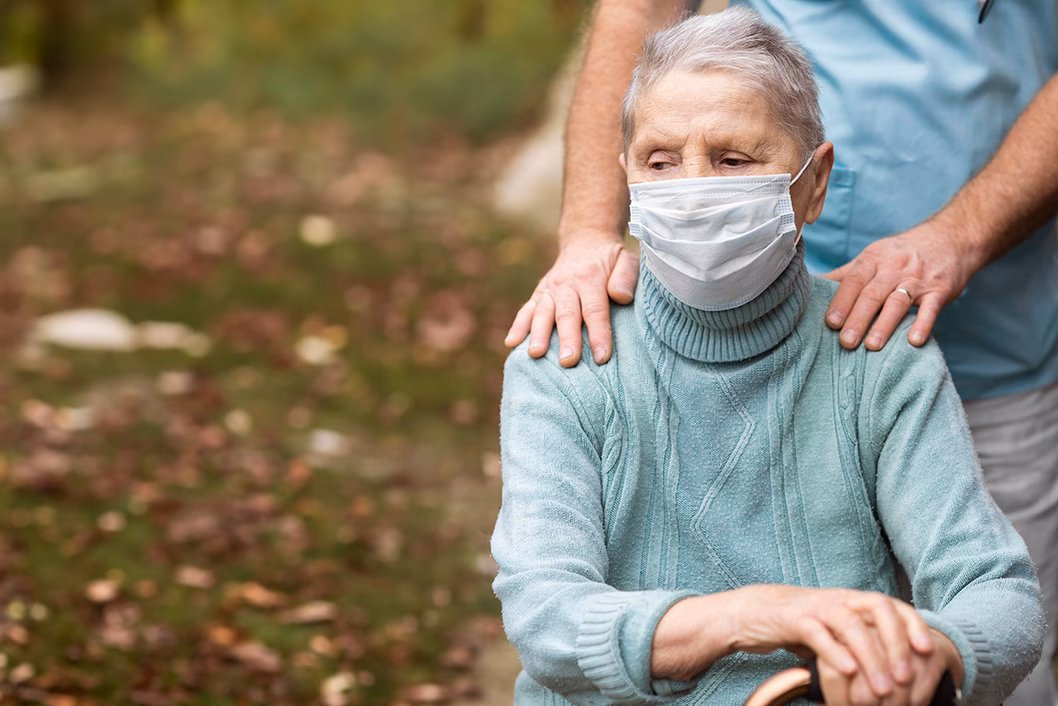Photo of a woman in a pale green jumper wearing a mask