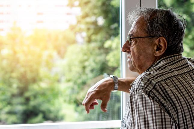 Image of an older Southern European man looking out of a window