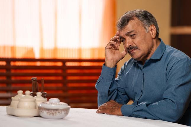 Photo of a seated man with his hand to his head