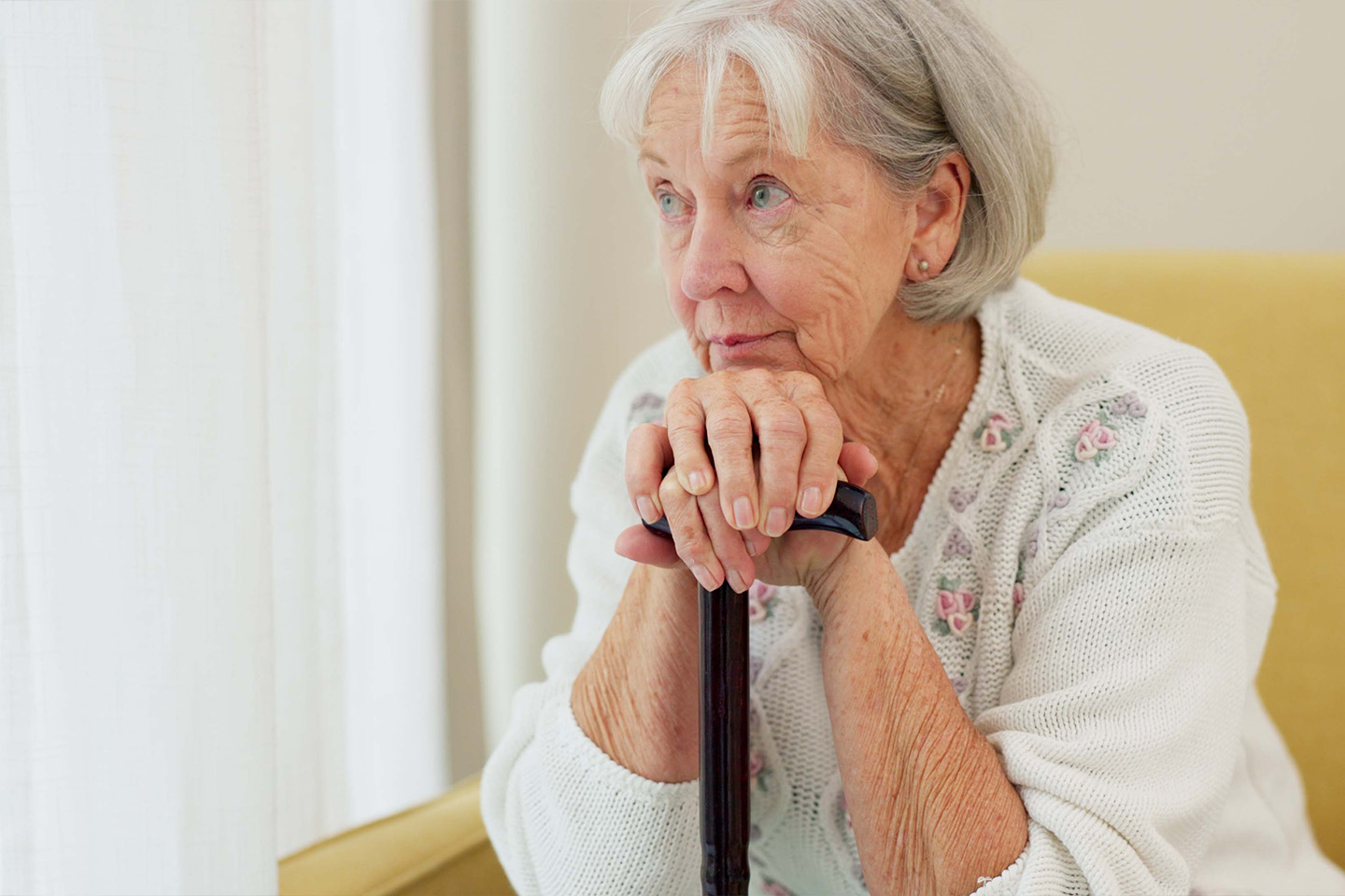 Photo of a pensive woman leaning on her walking stick
