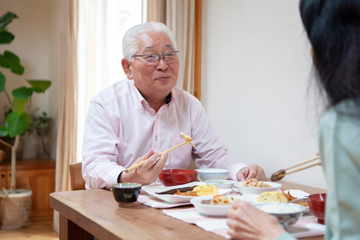 Image of an older Asian man eating a meal with a younger family member