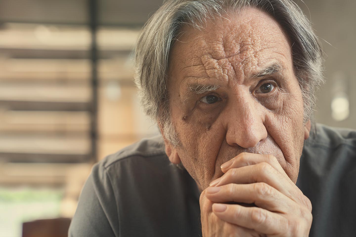 Photo of a man in gray with hands clasped