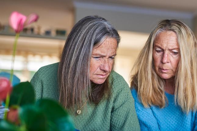 Photo of two women with an out of focus flower in the foreground