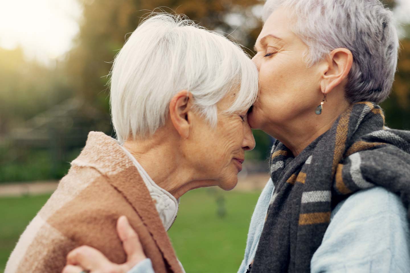 Photo of one woman kissing another woman's forehead