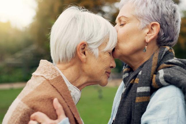 Photo of one woman kissing another woman's forehead