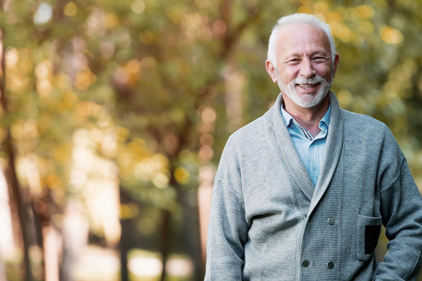 Photo of a smiling man in a cardigan outdoors