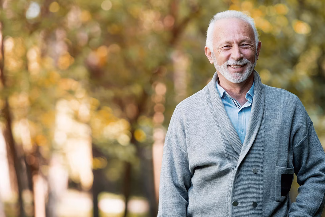Photo of a smiling man in a cardigan outdoors