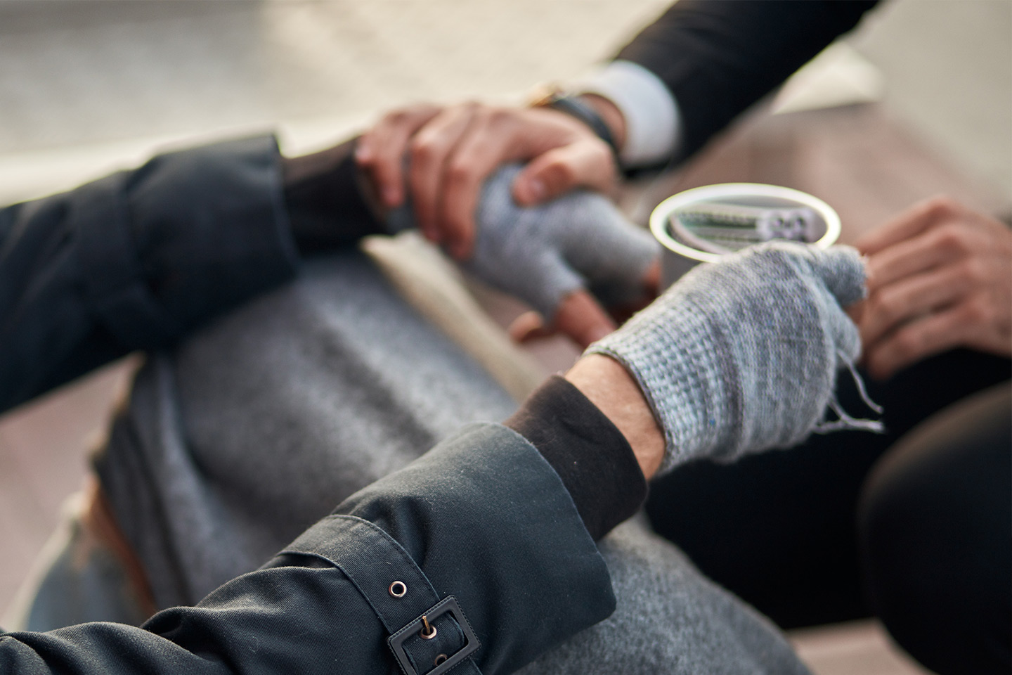 Photo of four hands an a cup with money in it