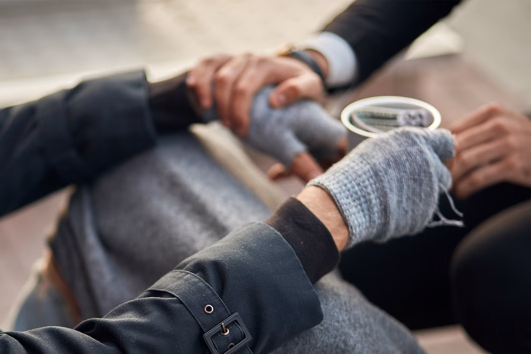 Photo of four hands an a cup with money in it