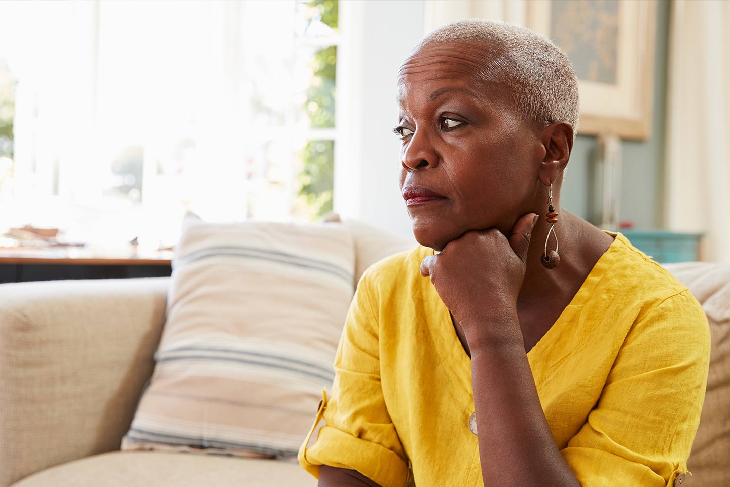Photo of woman in a yellow linen top resting her chin on her hand