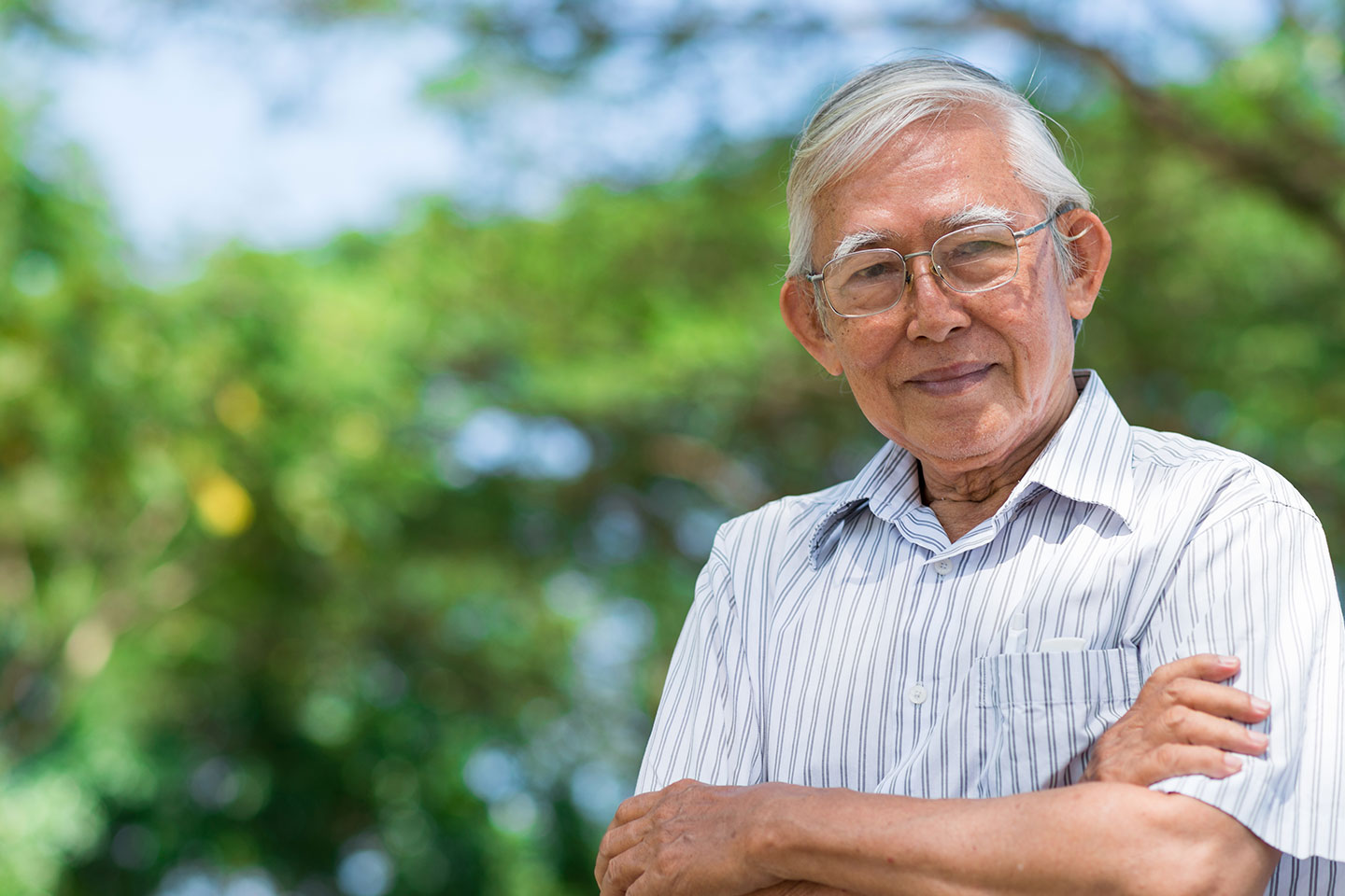 Image of an older asian man standing outside