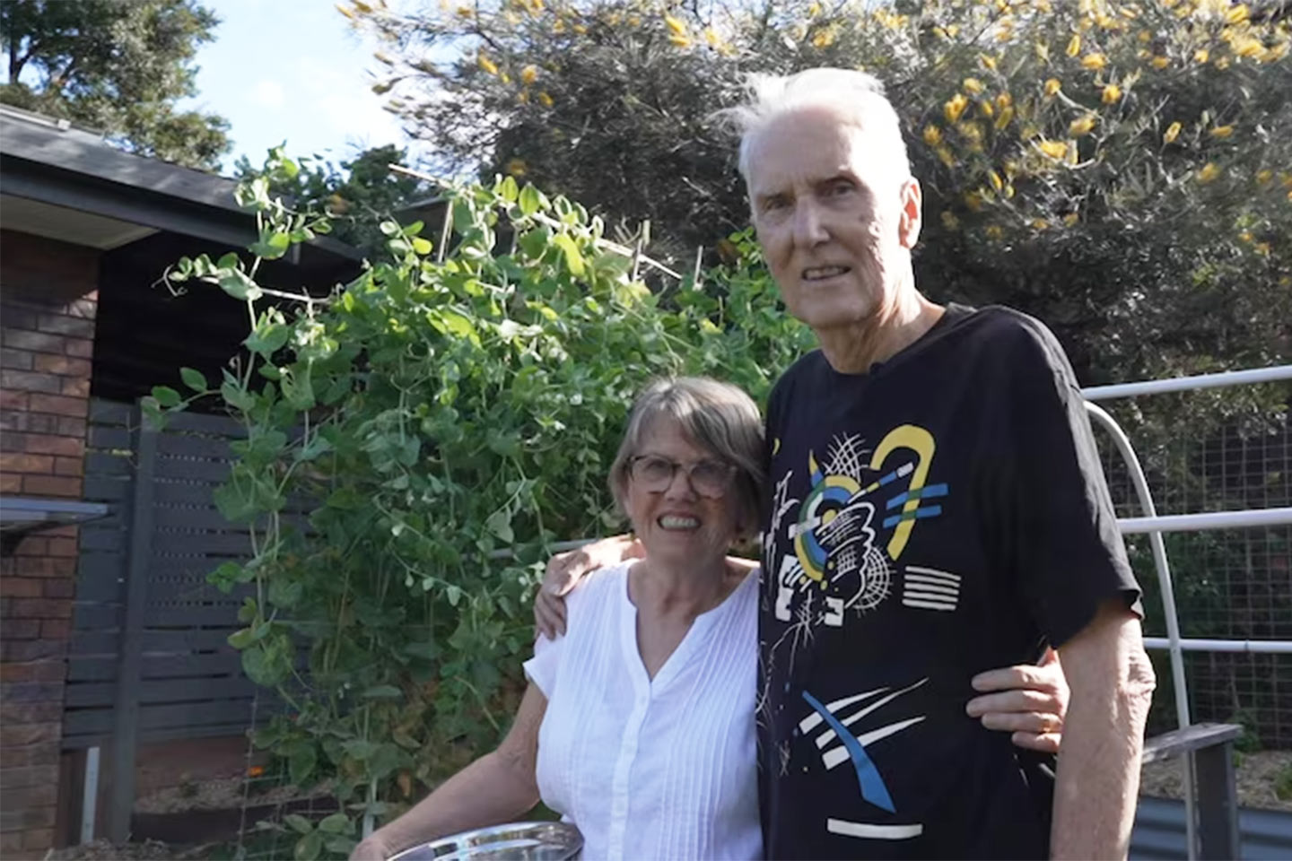 Photo of an older couple in a leafy backyard