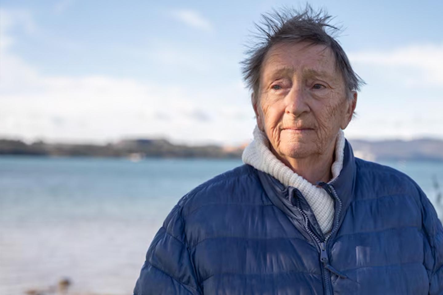 Photo of a woman by the beach wearing a blue parka