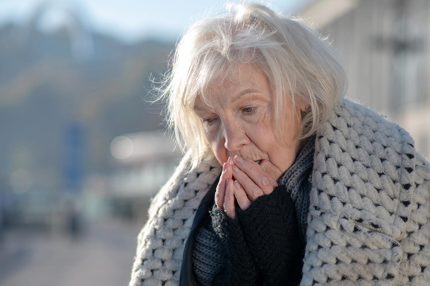 Photo of a woman wearing a warm coat and blowing on her fingers