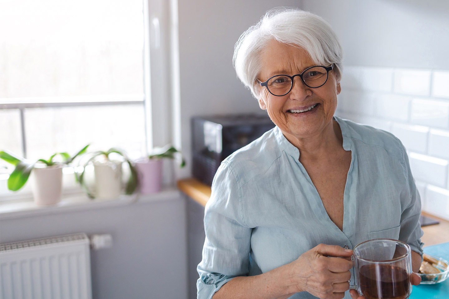 Image of an older southern European woman holding a mug of black coffee