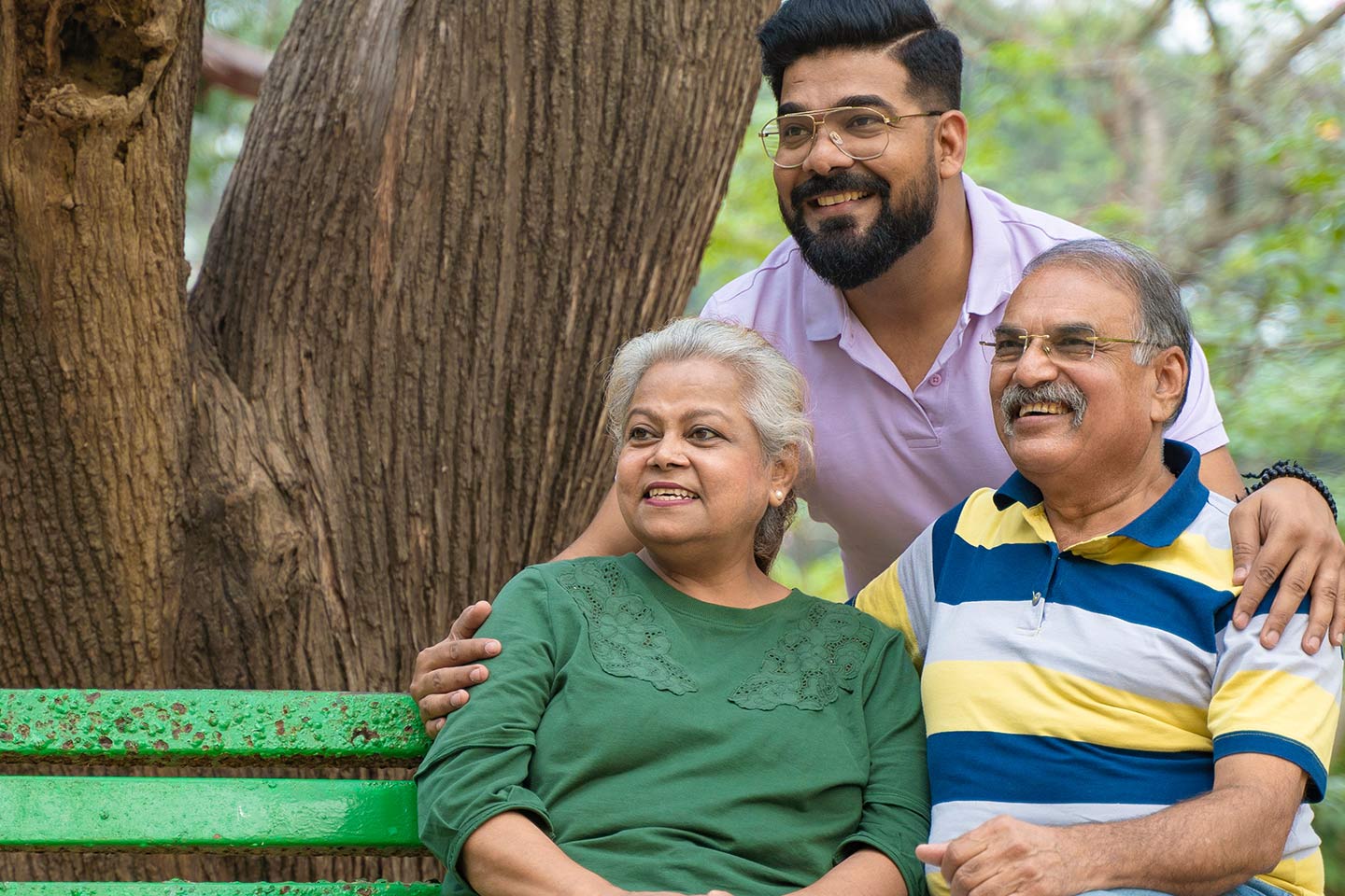 Photo of parents and their adult child sitting on a garden bench