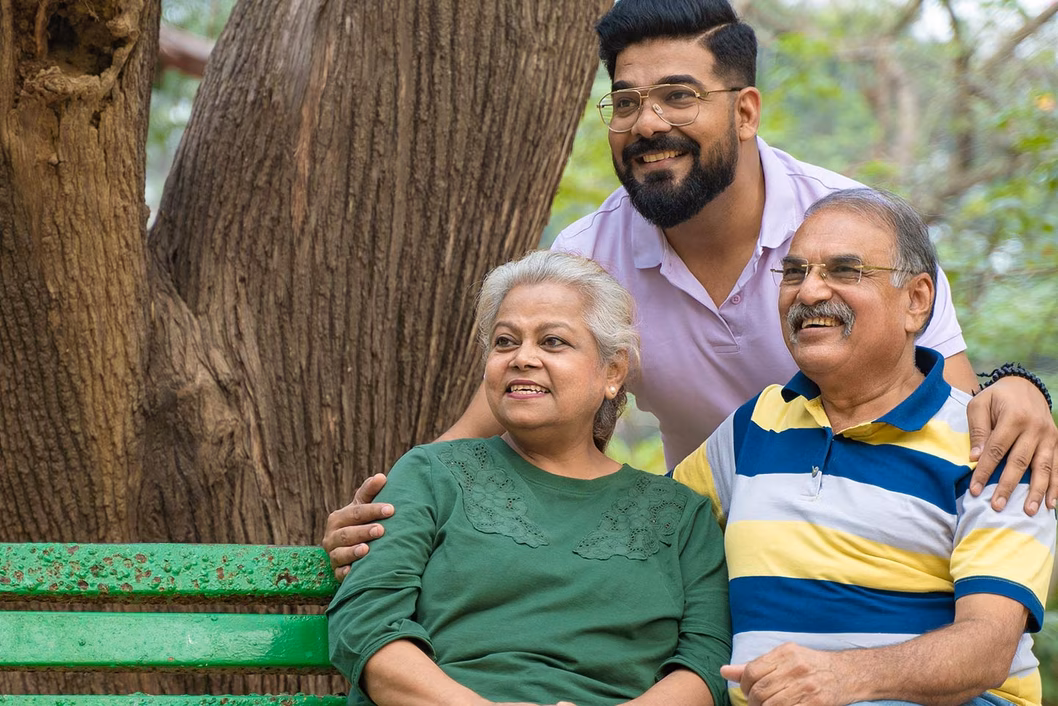 Photo of parents and their adult child sitting on a garden bench