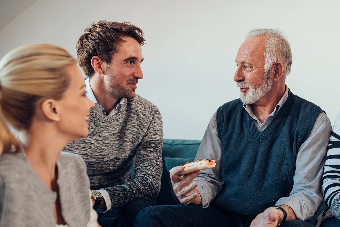 Photo of older man chatting with younger couple over pizza