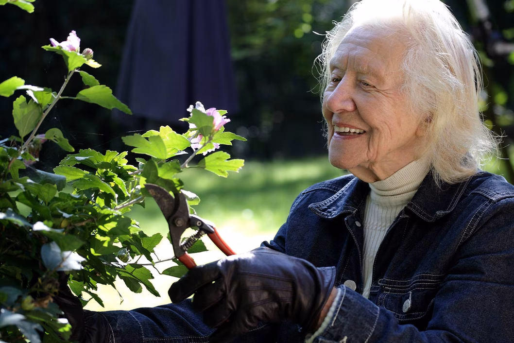 Photo of a woman happily pruning in her garden