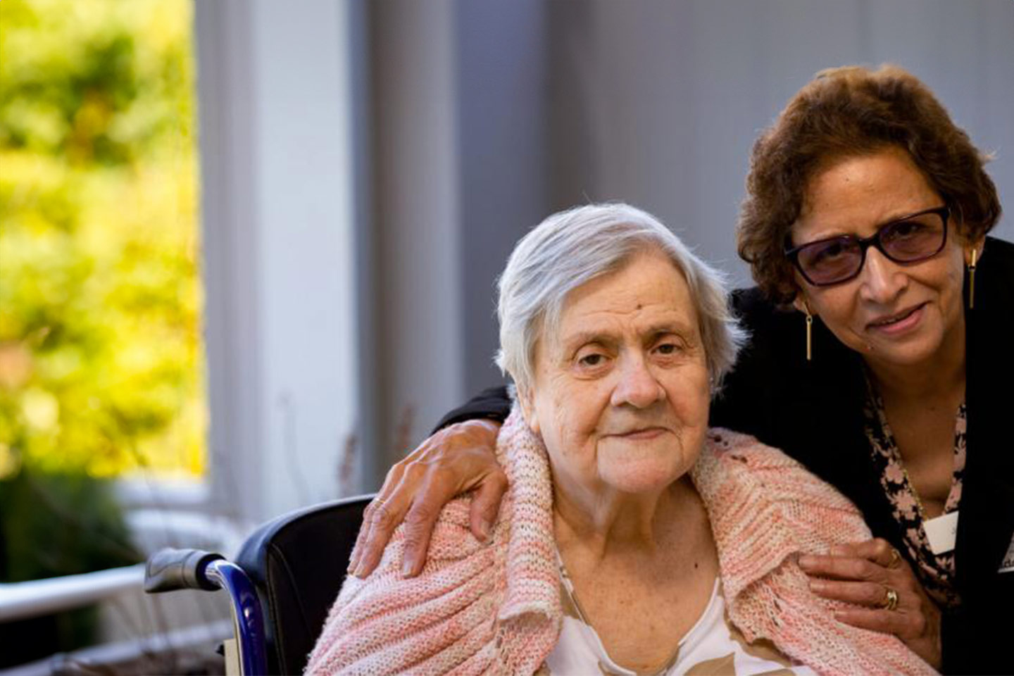 Photo of a visitor with arms around a senior lady's shoulders