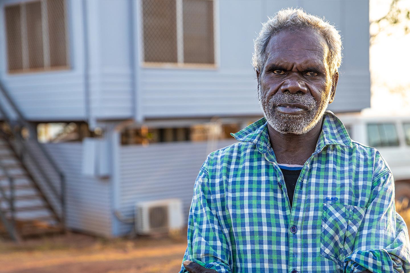 Photo of a man standing in front of a home on stilts