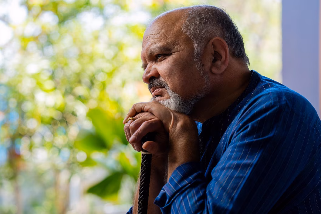 Photo of a bearded man leaning on his walking stick
