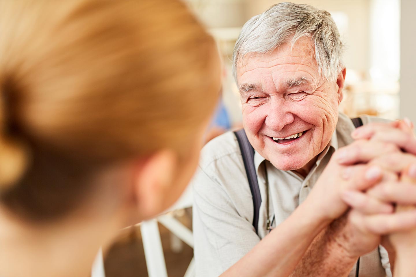 Photo of a man laughing wearing braces over his khaki shirt