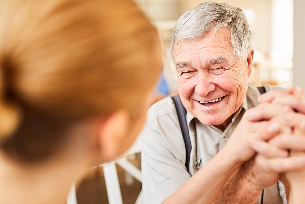 Photo of a man laughing wearing braces over his khaki shirt