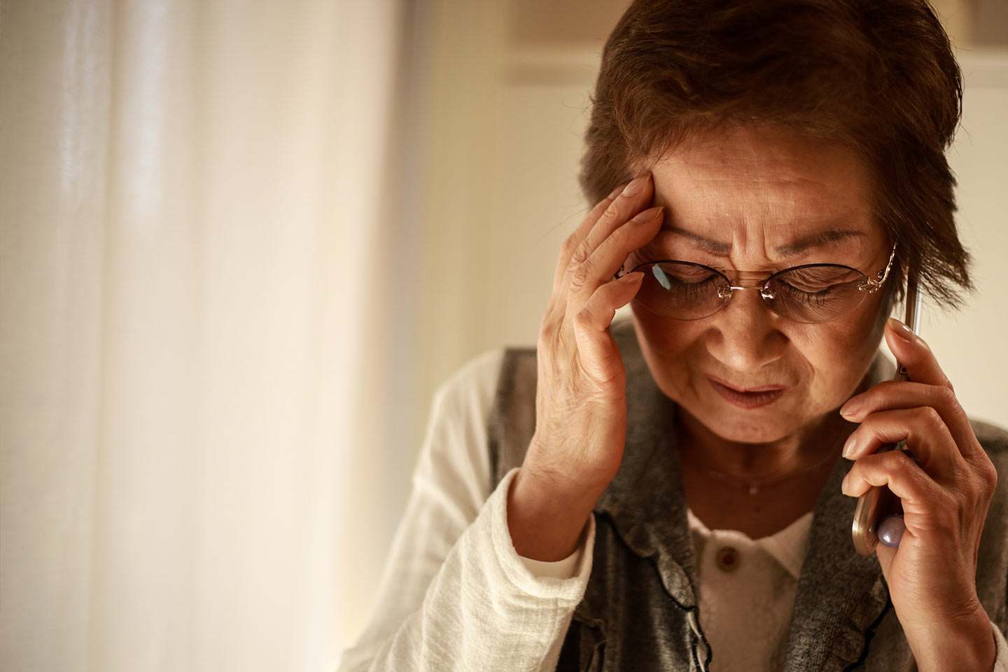 Photo of a woman on the phone with her hand to her forehead