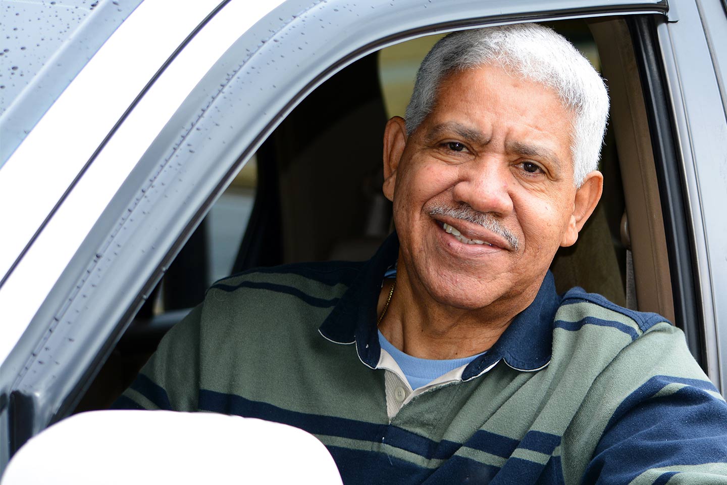 Photo of a man in a navy and green polo in a car