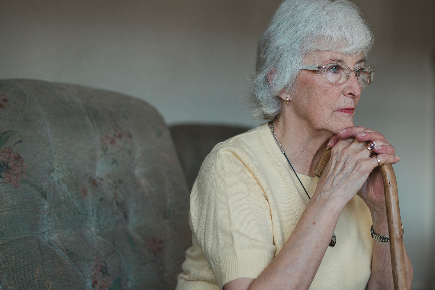 Photo of a woman leaning her chin on her walking stick
