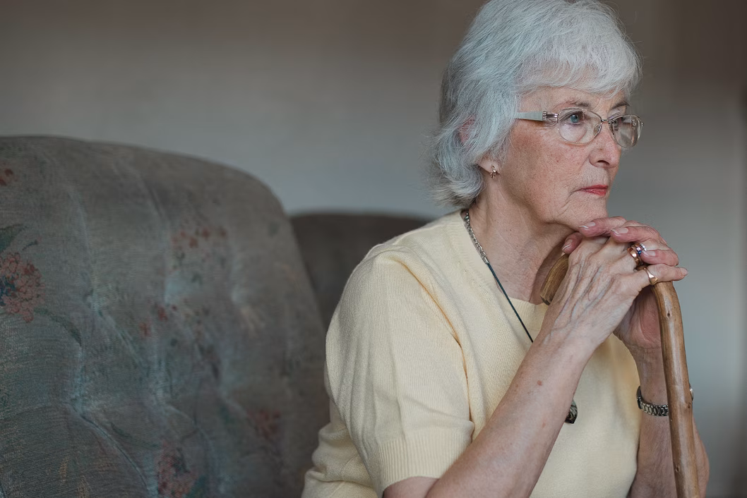 Photo of a woman leaning her chin on her walking stick