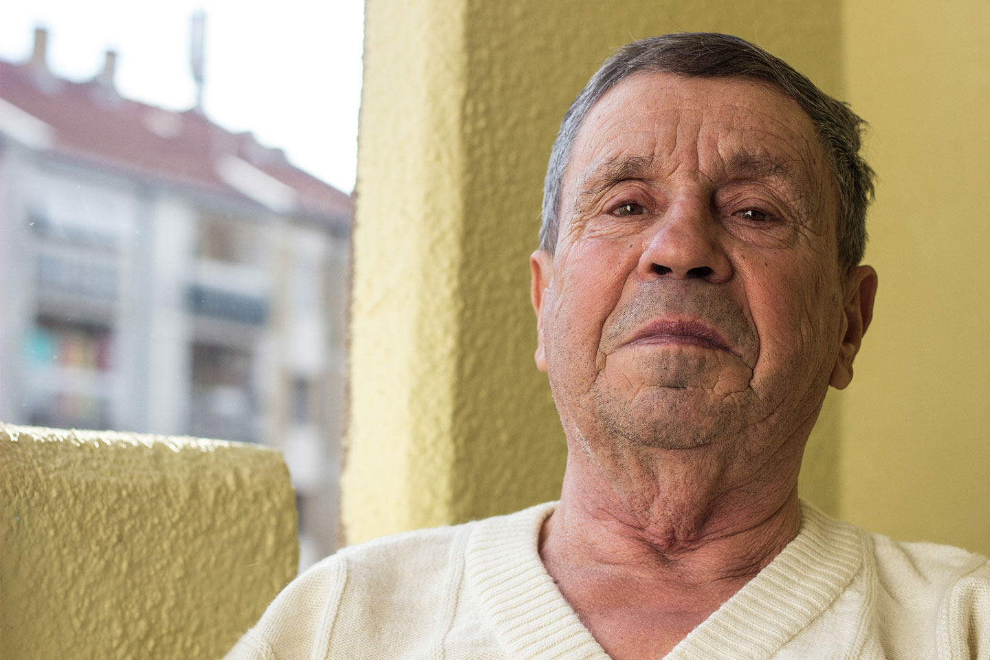 Photo of a man in a cream pullover in front of a butter yellow wall